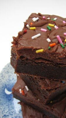 three chocolate brownies stacked on top of each other with sprinkles and frosting