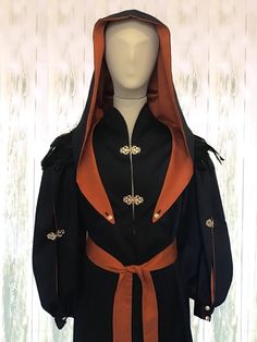 a mannequin wearing a black and orange outfit with an orange sash around its neck