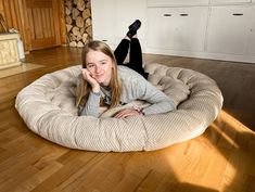 a woman laying on top of a dog bed