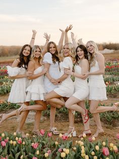 a group of women standing next to each other in front of tulips and flowers