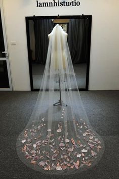 the back of a wedding veil with pink flowers on it in front of a doorway