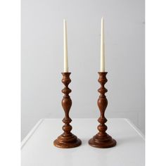 two wooden candlesticks sitting on top of a white table