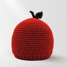 a crocheted red beanie with a green leaf on top