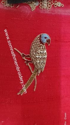 an embroidered bird sitting on top of a red piece of cloth