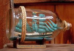 a glass ship in a bottle on a wooden table with rope and wood planks