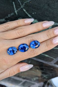 a woman's hand with three blue stones on it and one is wearing a ring