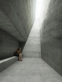 a woman sitting on the ground in an empty concrete room with stairs leading up to it