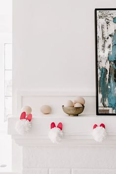 eggs are sitting on the mantle in front of a painting and two bowls filled with water