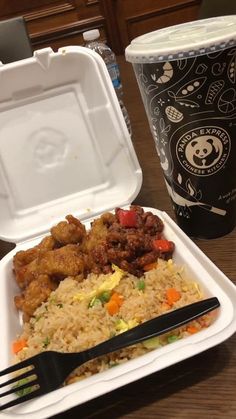 a plastic container filled with rice, meat and veggies next to a cup of coffee