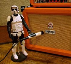 a star wars action figure is posed next to an orange amperator guitar amplifier