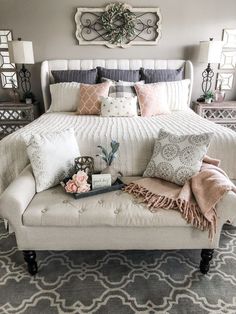 a white bed with pillows and blankets on the headboard, along with other decorative items