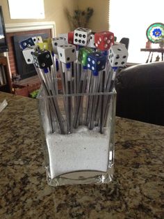 a glass filled with dice and sand on top of a counter