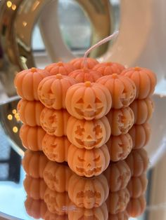 a stack of carved pumpkins sitting on top of a glass table next to a mirror