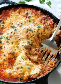 a close up of a casserole with meat and cheese on the side, next to a fork