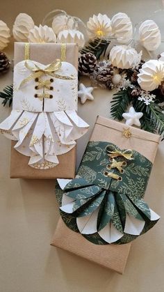 three small gift bags are sitting on a table next to some flowers and pine cones