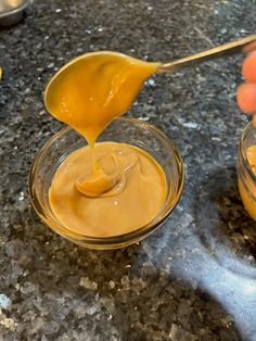 a person pouring peanut butter into small bowls on a granite countertop with other ingredients