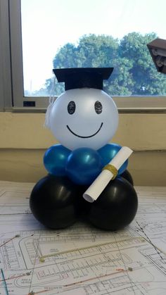 a balloon in the shape of a graduate sitting on top of a table with a diploma