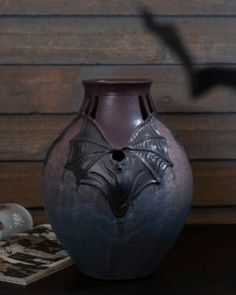 a purple vase sitting on top of a table next to a magazine and other items