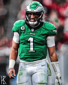 a close up of a football player wearing a green uniform and holding a white helmet