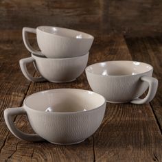 three white cups sitting on top of a wooden table