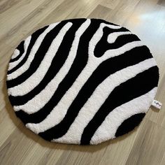 a black and white round rug on the floor with zebra print in the middle, sitting on top of a hard wood floor