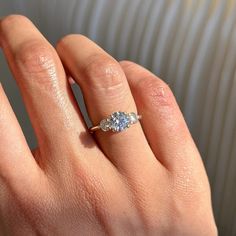 a woman's hand with a three stone ring on top of her left hand