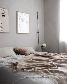 a bed with blankets and pillows in a bedroom next to two pictures on the wall