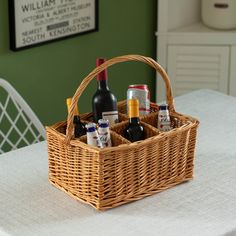 a wicker basket filled with bottles of wine on top of a white table cloth