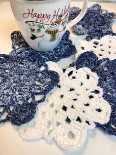 crocheted coasters on a table with a coffee cup and happy holidays mug