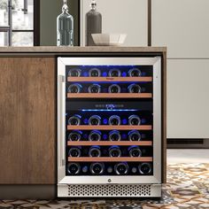 a wine cooler with many bottles in it on the floor next to a counter top