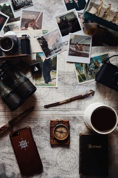 a table topped with lots of pictures and a camera next to a cup of coffee