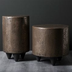 two metal stools sitting next to each other on a gray surface with black legs