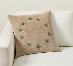 a white couch with a decorative pillow on it's back and an embroidered design on the cushion