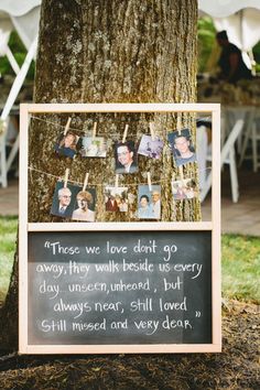 a chalkboard with pictures hanging from it next to a tree