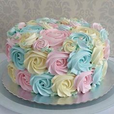 a cake decorated with pastel colored frosting roses on a silver platter against a wallpapered background