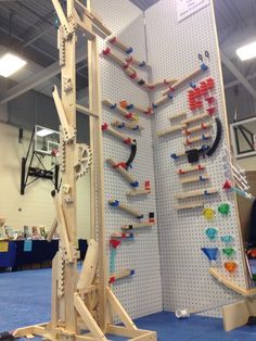 an indoor climbing wall with wooden pegs on the side and various pieces of wood attached to it