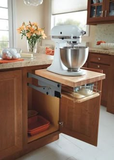 a kitchen scene with focus on the mixer in the cabinet drawer and an orange flower