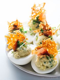 deviled eggs topped with bacon and garnish on a plate