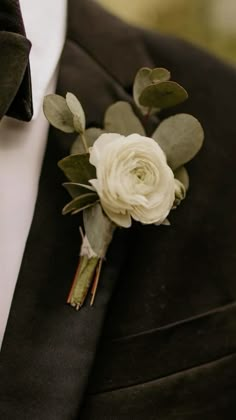 a boutonniere with white flowers and greenery on it's lapel