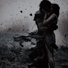 two people hugging in the middle of a field with birds flying overhead and rain falling down on them