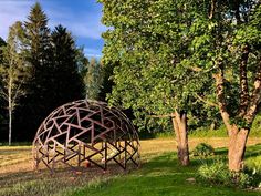 a large metal structure sitting in the middle of a field next to trees and grass