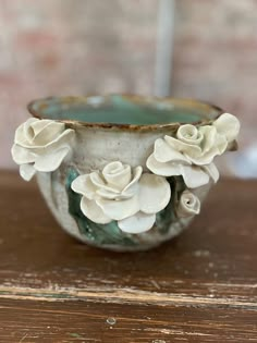 a white vase with flowers in it sitting on a table