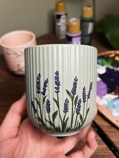 a hand holding a cup with lavender flowers painted on it