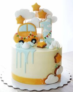 a birthday cake decorated with an orange and white bus, stars, and clouds on top