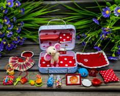 a small toy mouse in a suitcase surrounded by other toys and accessories on a wooden table