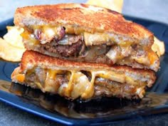 a grilled cheeseburger is on a blue plate with some potato wedges