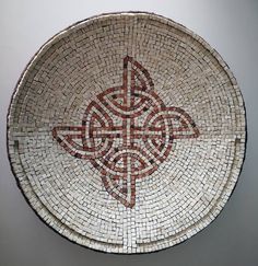 a decorative plate with an intricate design in the center on a white wall behind it