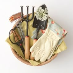 gardening tools in a basket with gloves and flowers