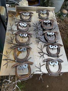 several metal objects with eyes and horns on them sitting on a table in front of some plants