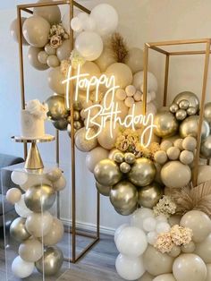 a happy birthday balloon arch with balloons and confetti on the top, surrounded by white and gold balloons